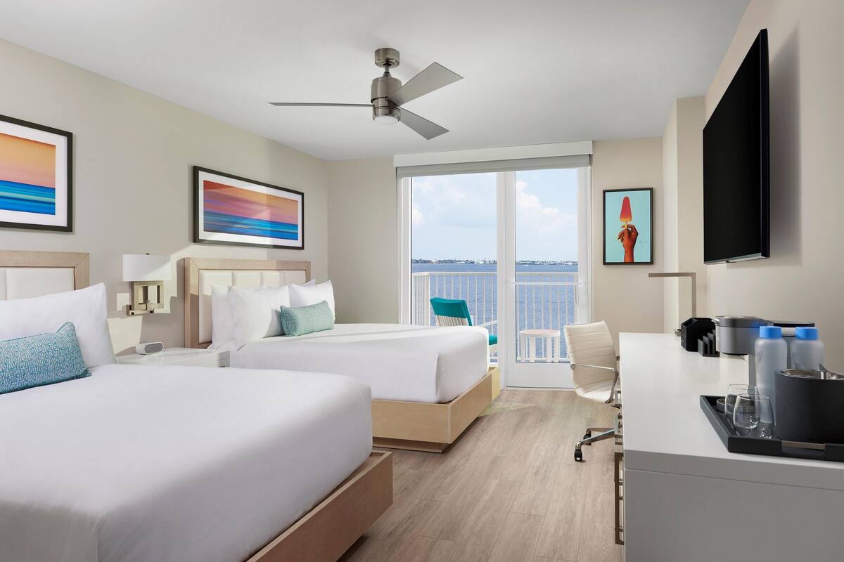Une chambre d’hôtel avec deux lits, un bureau, une télévision et un balcon avec vue.