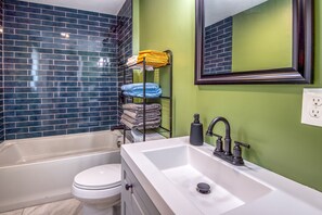 Ein Badezimmer mit Badewanne, Toilette und Waschbecken mit Spiegel darüber.