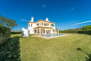 Stunning two-story house with a central entrance and beautifully manicured yard featuring a swimming pool.