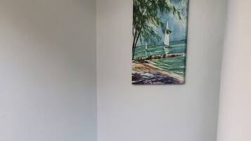 Una stanza con una scrivania nera, una poltrona da ufficio nera e un quadro raffigurante un faro su una spiaggia.