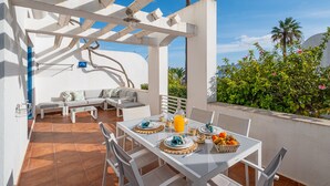 An outdoor patio with a white table set for breakfast, a sofa, and a pergola structure. - All Dreams Villa - Windmill Hill By Dreamplaces (Albufeira)