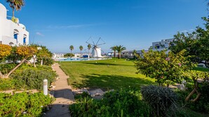 A windmill, a pool, and a pathway in a sunny outdoor setting. - All Dreams Villa - Windmill Hill By Dreamplaces (Albufeira)