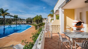 A poolside area with a barbecue and outdoor seating.