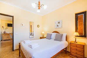 Une chambre à coucher bien rangée, avec un grand lit, des lampes de chevet, une commode et un miroir.