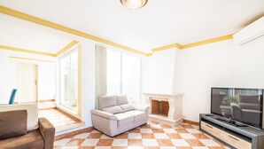 Una sala de estar con sofá, televisión y chimenea.
