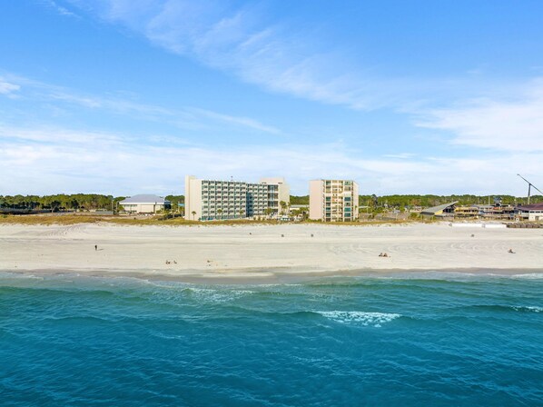 Un hotel frente al mar con varias construcciones, una playa de arena y el océano.