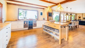 A spacious kitchen with wooden beams, a large window, and a dining area with chairs. - Casa Picota-Countryside & Pool (Boliqueime)