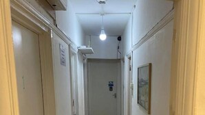 A narrow hallway with wooden flooring, white walls, and a ceiling light. - Rahal Hotel Hackney London (London)