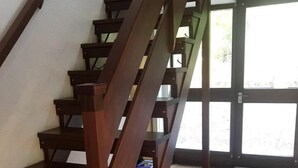 A wooden staircase with a red carpet leading to a door. - Midcentury 3-bed House in Gairloch (Gairloch)