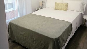 Quarto bem arrumado com uma cama, mesas de cabeceira, um ventilador de teto e uma janela com cortinas.