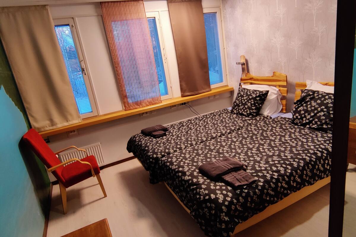 A bedroom with a bed, a chair, a window, and a radiator.