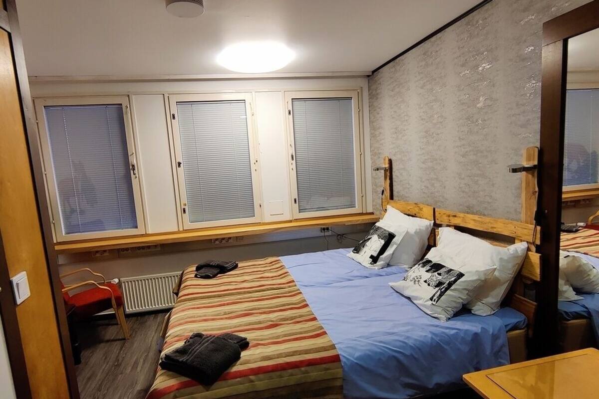 A room with a bed, a chair, a table, and a window with blinds.