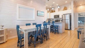 A modern kitchen with white cabinetry, stainless steel appliances, and a central island with bar stools.