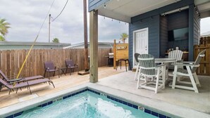 A pool area with lounge chairs, a table, and a covered patio.