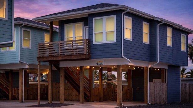 A two-story building with a balcony, wooden deck, and string lights.