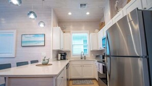 A modern kitchen with white cabinetry, stainless steel appliances, and pendant lighting.