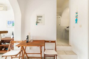 Cozy retreat with a dining table for two, a coffee machine, and a shower area.