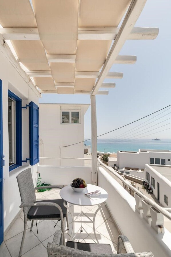 Enjoy the ocean view from this balcony with a table and two chairs.