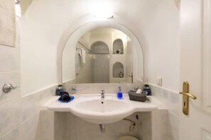 Bathroom features a large arched mirror, white sink, and toilet.