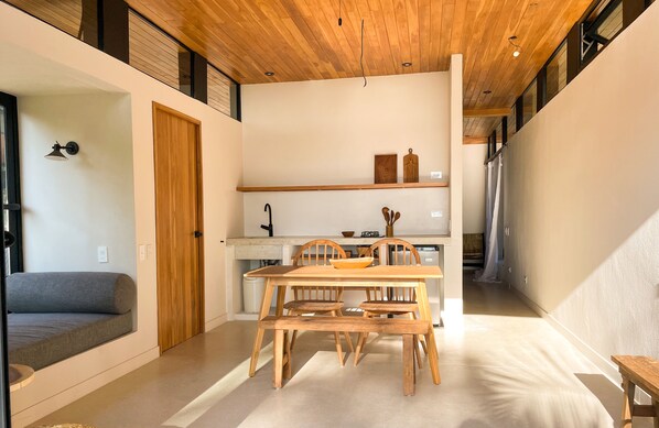 A modern kitchen with wooden cabinets, a dining table, and chairs. - PURAPURA SANTA TERESA (Cóbano)