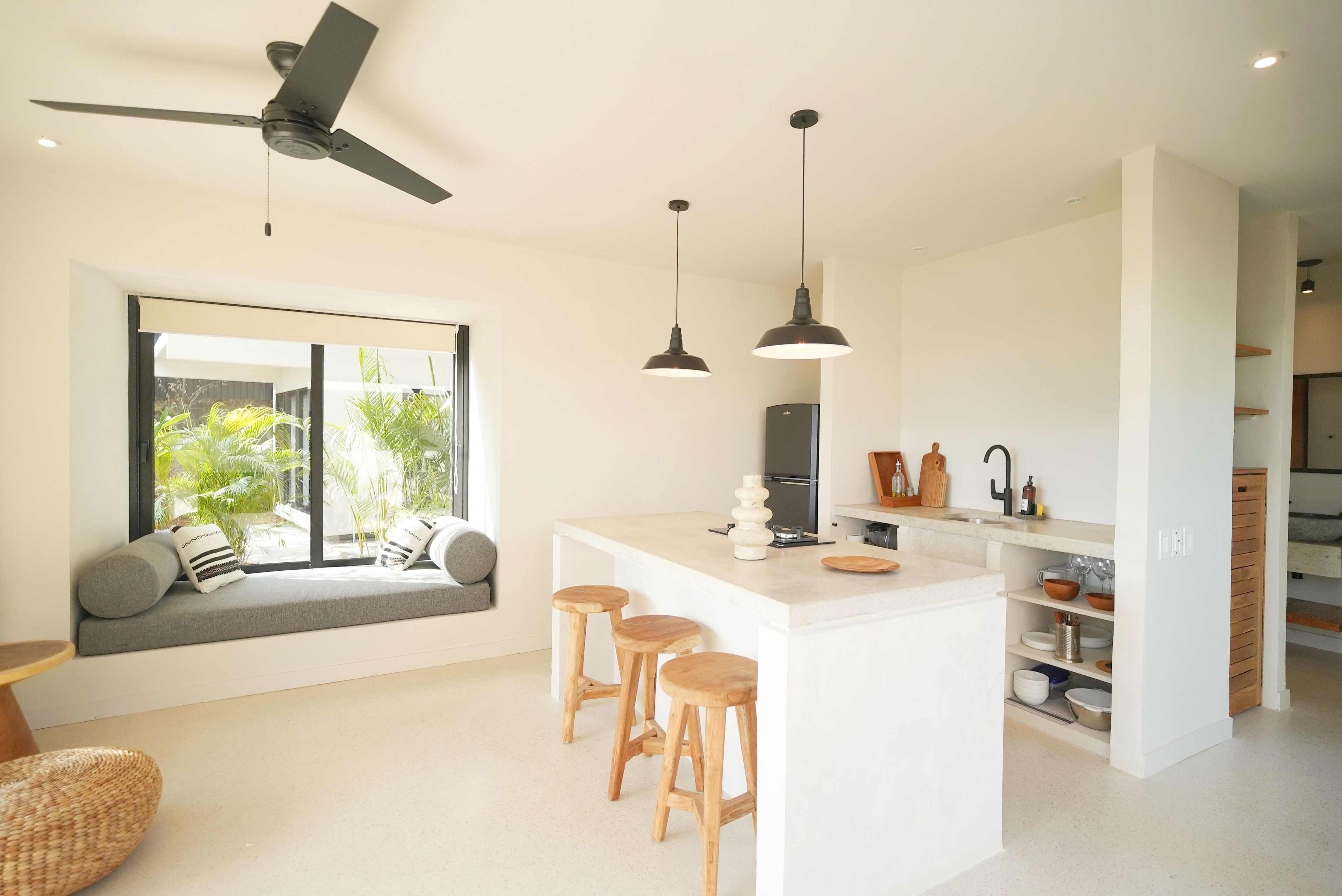 Una cucina moderna con isola centrale, sgabelli da bar, illuminazione a sospensione e ventola a soffitto.