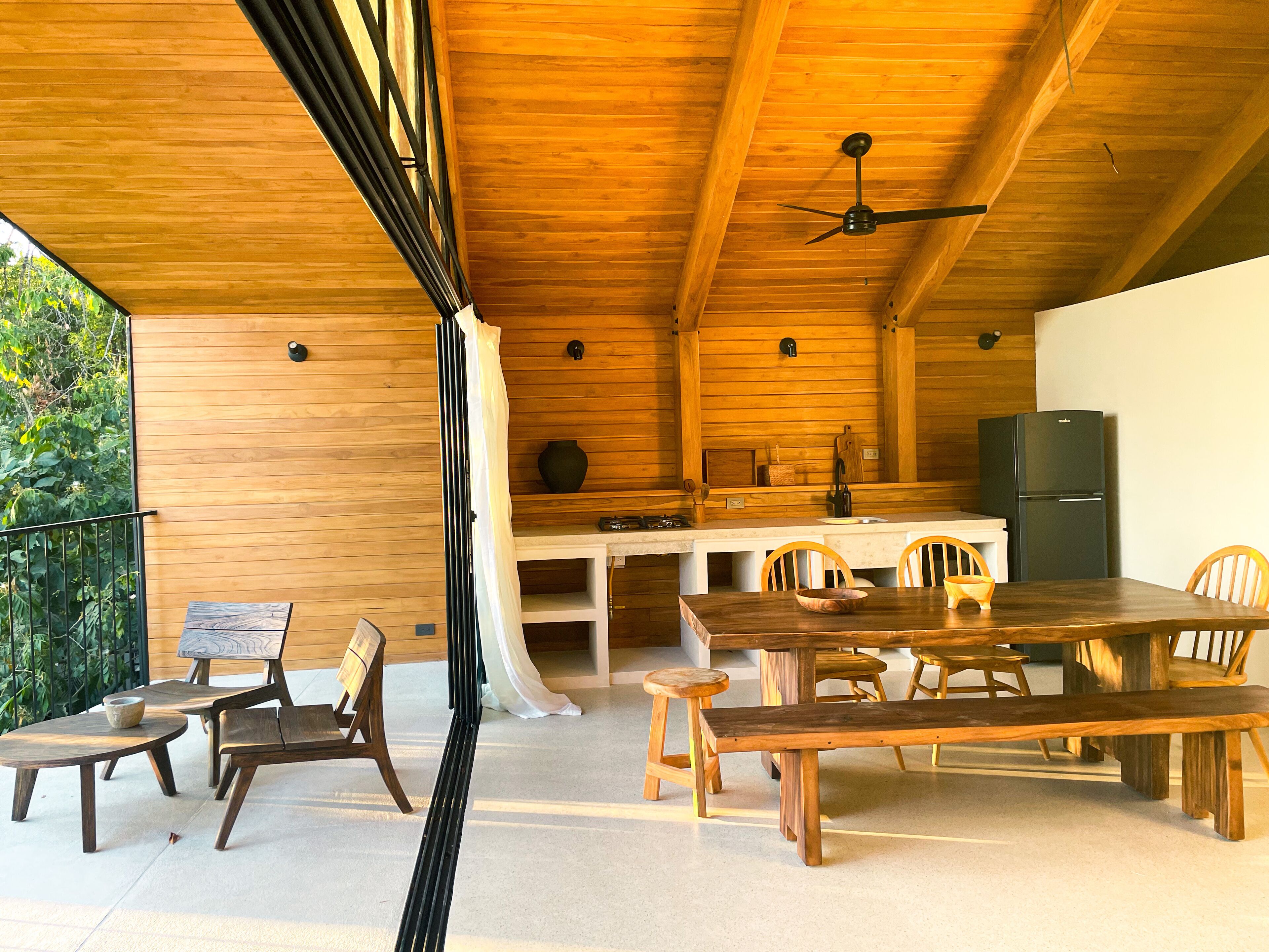 A wooden interior with a dining area, kitchen, and a ceiling fan.