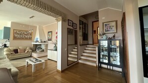 A spacious living room with a sofa, coffee table, and a staircase leading to another level. - Villa of flowers, nestled in the green between the sea and the mountains. (Poggio dei Pini)