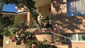 A building with a stone staircase, potted plants, and a balcony. - Villa of flowers, nestled in the green between the sea and the mountains. (Poggio dei Pini)