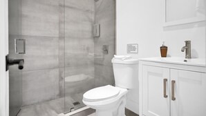 A modern bathroom with a glass-enclosed shower, a white toilet, and a white vanity with a mirror and a soap dispenser. - Modern Villa 1 in Miami close to Brickell, Wynwood, near everything (Miami)