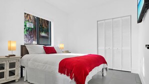 A bedroom with a large bed, white walls, a TV mounted on the wall, and a white wardrobe. - Modern Villa 1 in Miami close to Brickell, Wynwood, near everything (Miami)
