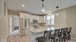 A modern kitchen with white cabinetry, stainless steel appliances, and a central island with bar stools.