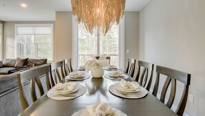 A dining room with a long table set for six, featuring woven placemats and white napkins.