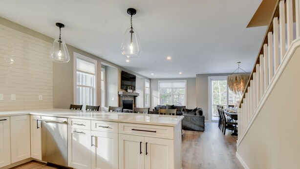 A spacious kitchen with a large island, white cabinetry, and pendant lighting.