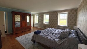 A bedroom with a large bed, a wooden dresser, and two windows. - Peaceful Retreat in the Countryside with Farm Animals and Play Area (Boyds)