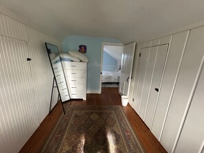 A narrow hallway with a wooden floor, a white dresser, a bed, and a white wardrobe. - Peaceful Retreat in the Countryside with Farm Animals and Play Area (Boyds)
