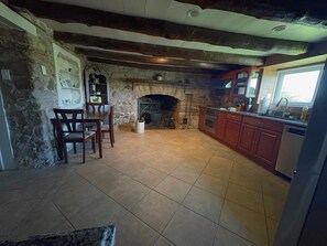 A kitchen with a stone fireplace, wooden cabinets, and a tiled floor. - Peaceful Retreat in the Countryside with Farm Animals and Play Area (Boyds)