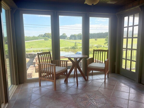 A conservatory with a view of a green field and a pond. - Peaceful Retreat in the Countryside with Farm Animals and Play Area (Boyds)