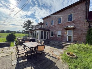 A stone building with a balcony, outdoor seating, and a view of a green field. - Peaceful Retreat in the Countryside with Farm Animals and Play Area (Boyds)