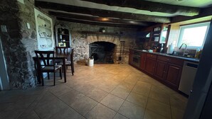 A kitchen with a stone fireplace, wooden cabinets, and a tiled floor. - Peaceful Retreat in the Countryside with Farm Animals and Play Area (Boyds)