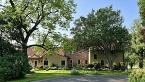 A residential area with two houses, a paved driveway, and well-maintained lawns.