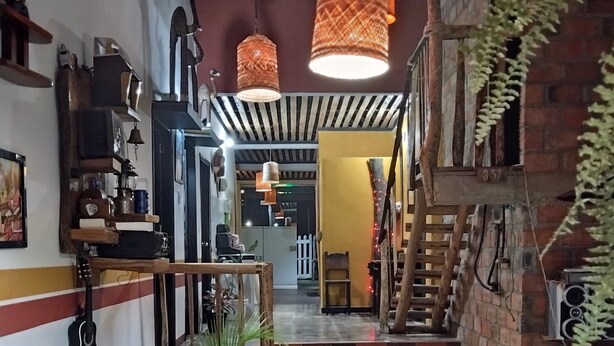 A staircase leading to a second floor, with a wooden bench and a hanging plant in the foreground.