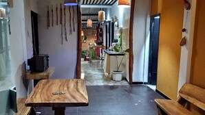 A modern interior with a wooden table, hanging decorations, and a view into a kitchen area.