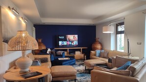 En moderne stue med et stort fladskærms-tv, behagelige møbler og en dekorativ lampe.