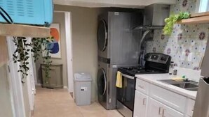 Une cuisine de taille réduite équipée d’un lave-linge, d’une cuisinière et d’un évier.