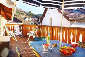 Eine Holzterrasse mit Tisch, Stühlen und Sonnenschirmen.