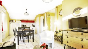 A compact living space with a dining area, kitchenette, and a TV on a wooden cabinet. - Comme Chez Soi - Vue montagne et garage privé (La Bresse)