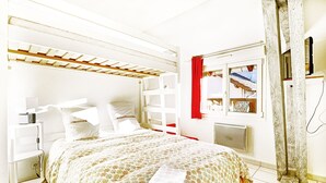 A bedroom with a bunk bed, a bedside table, a window with a view, and a red curtain. - Comme Chez Soi - Vue montagne et garage privé (La Bresse)