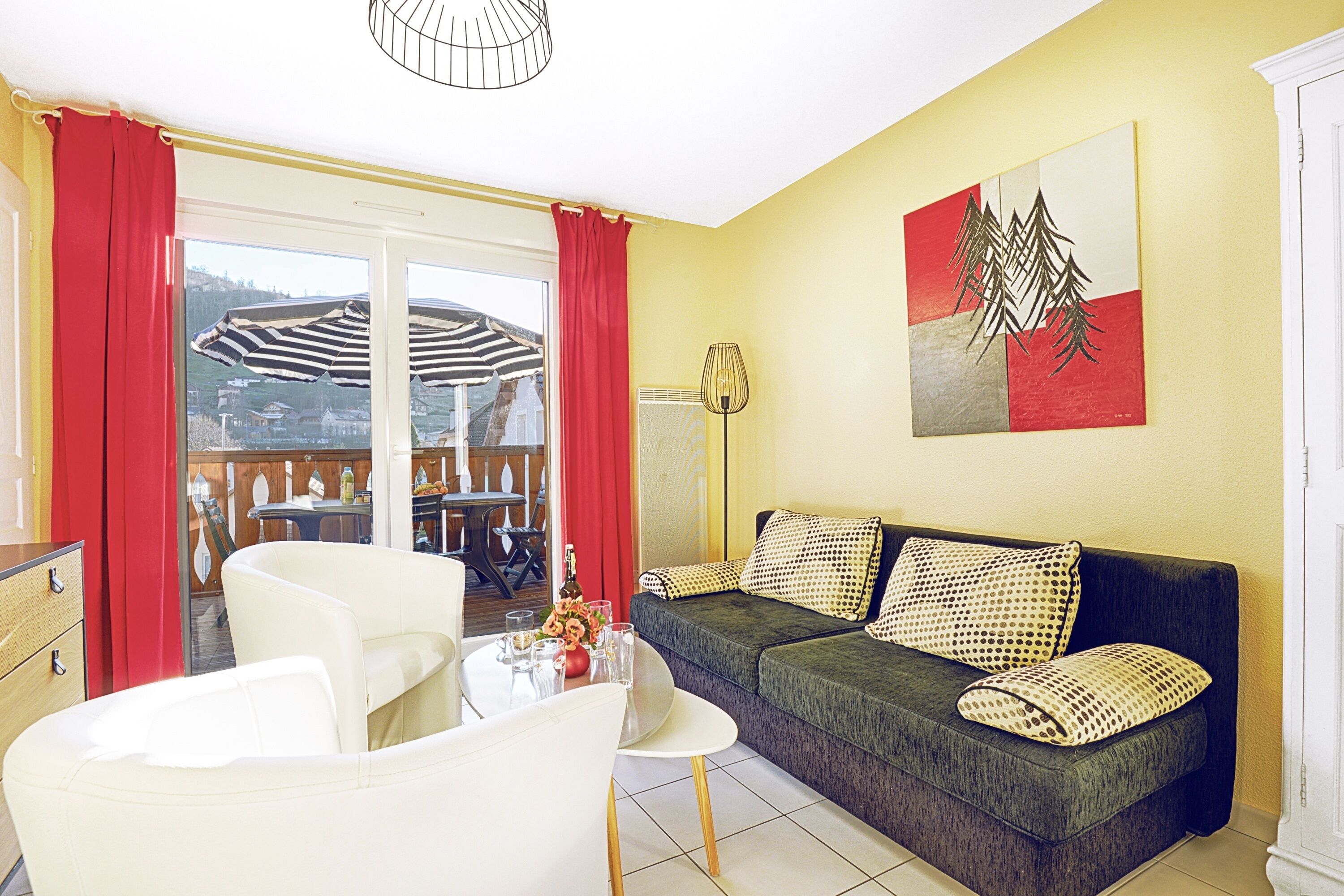 Una sala de estar con sofá, sillas, una mesa y vistas al exterior.