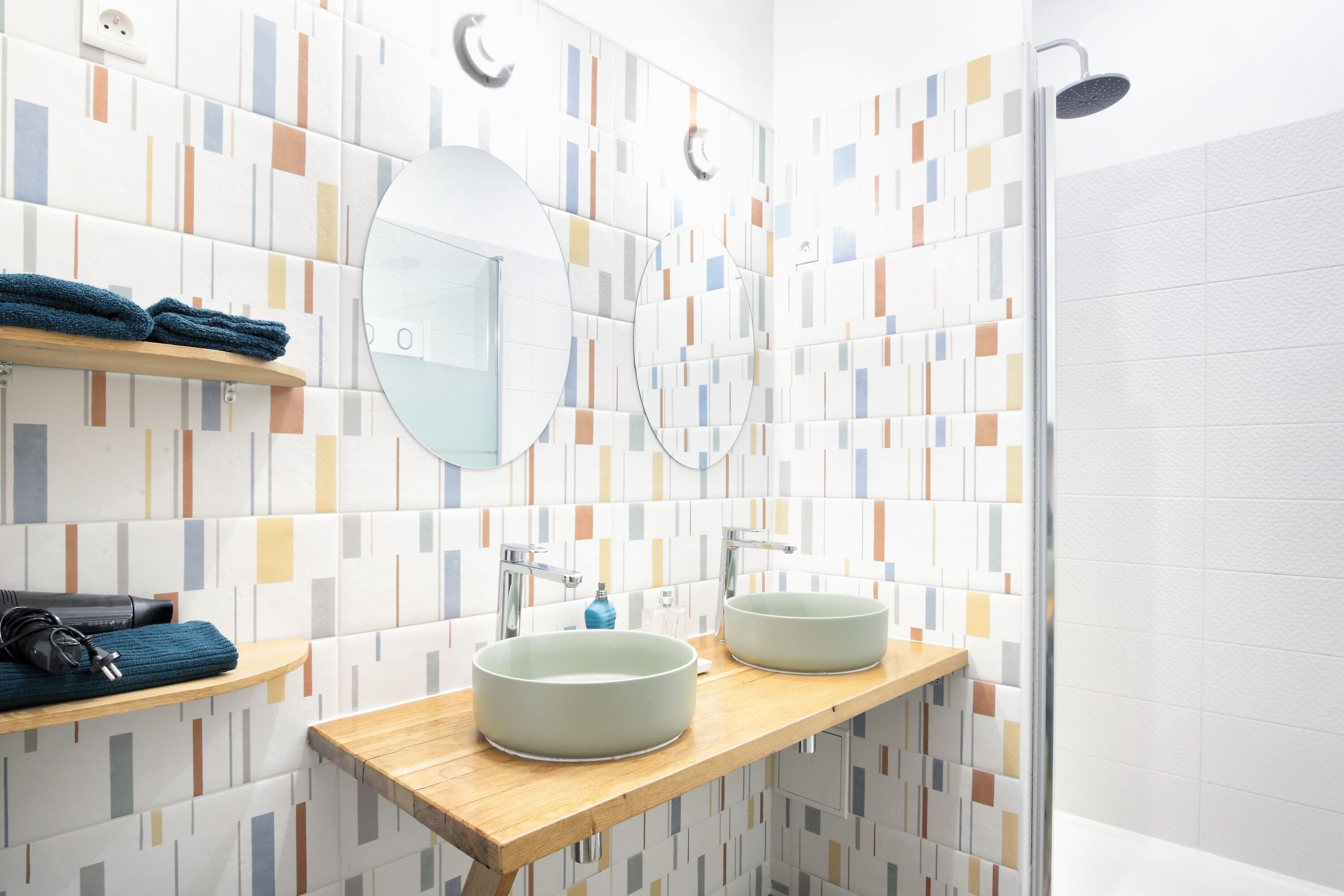 Une salle de bain moderne avec deux vasques rondes, un meuble-lavabo en bois, un miroir et une douche.