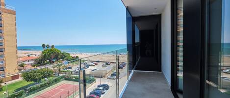 A balcony with a view of the beach and parking area.
